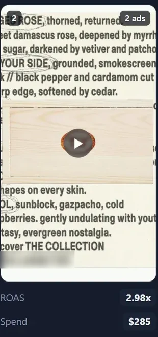 Rank 2 on the ROAS board. A video still set in type, describing a rose scent around a wooden box, badged 2 ads, returning 2.98x on $285 of spend.
